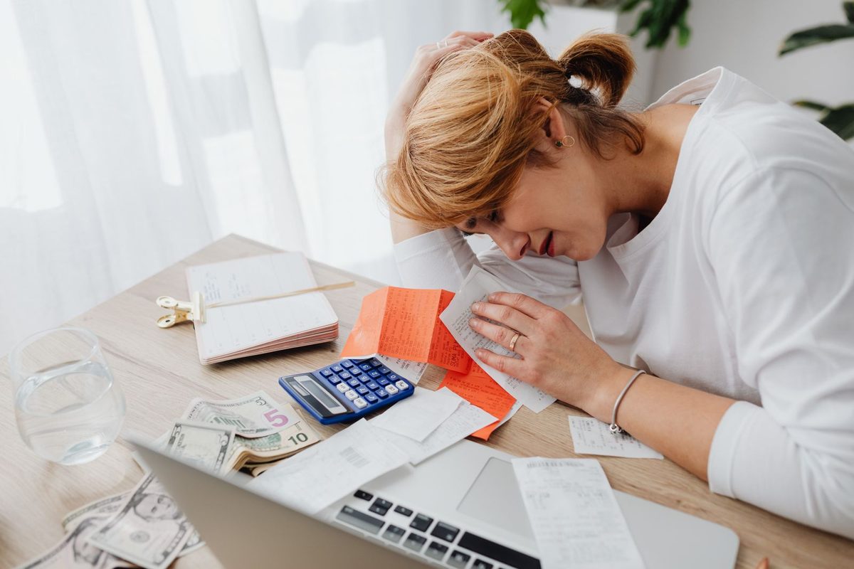 Femme submergée par des papiers et une calculatrice