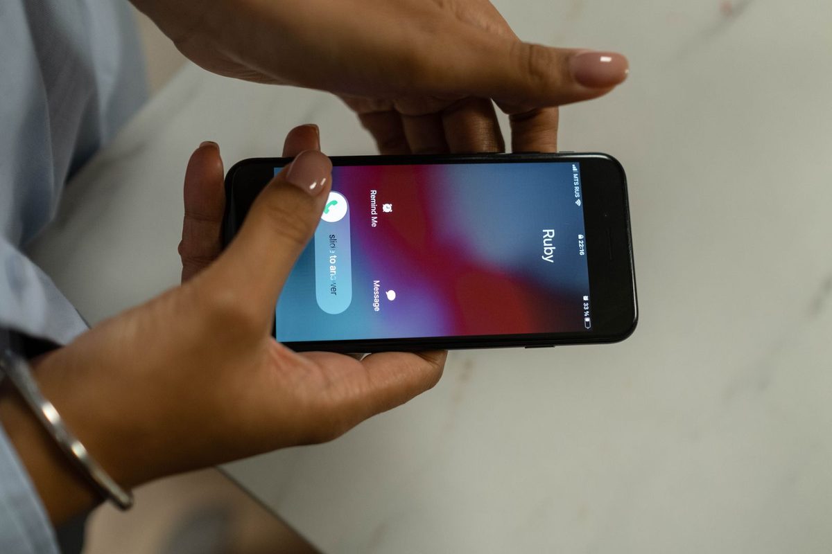 Appel entrant affiché sur l'écran d'un téléphone tenu à deux mains