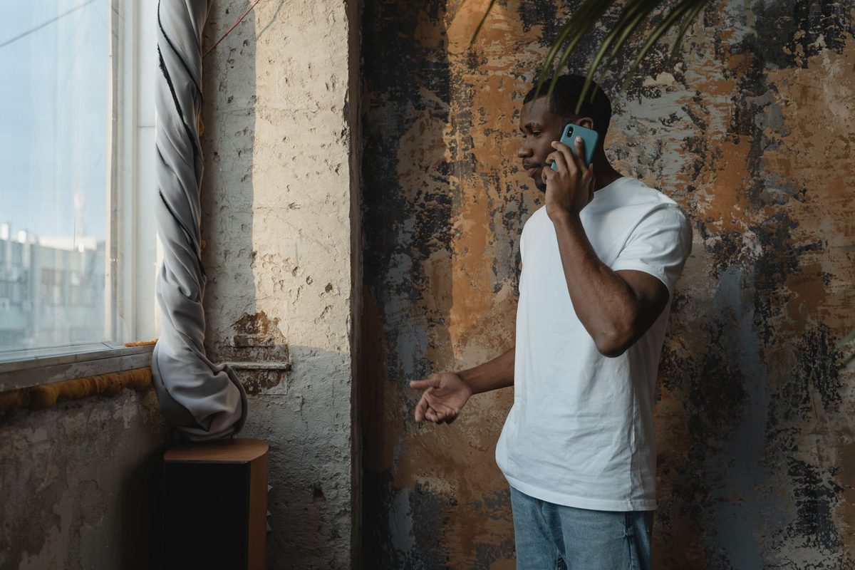 Homme au téléphone, adossé à un mur