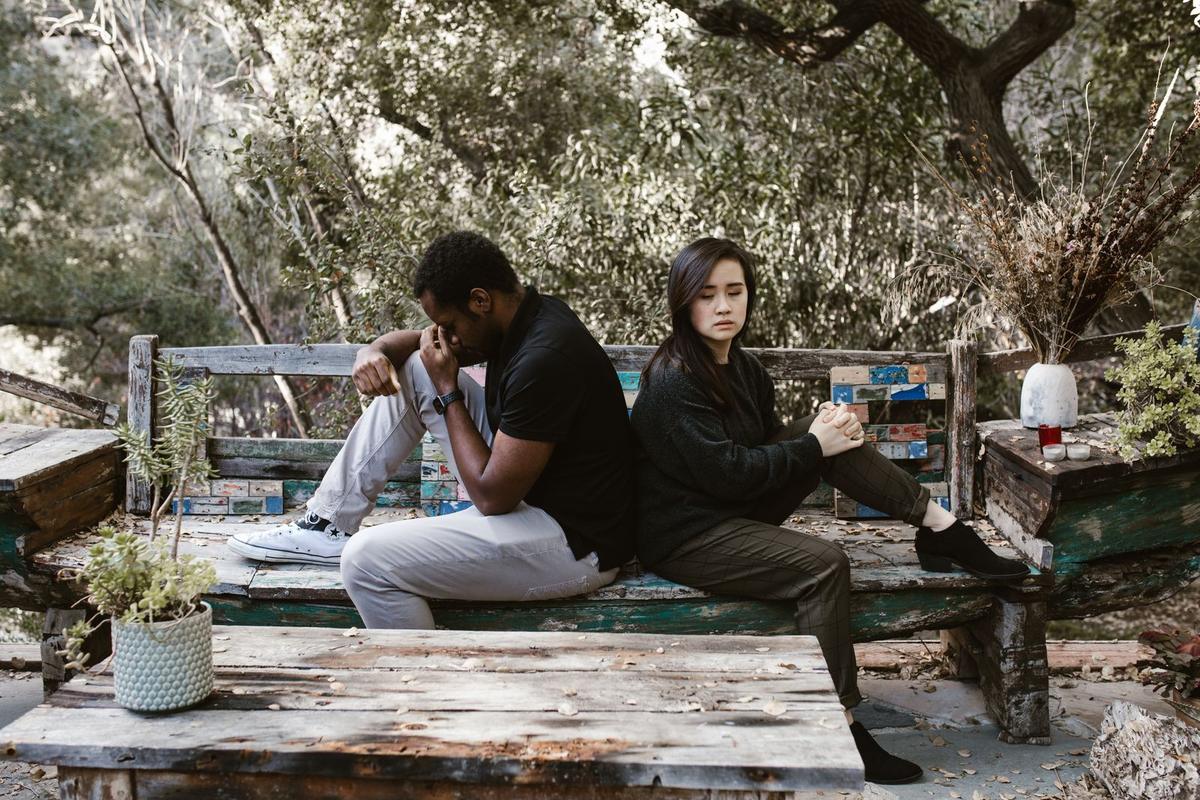 Couple assis dos à dos sur un banc