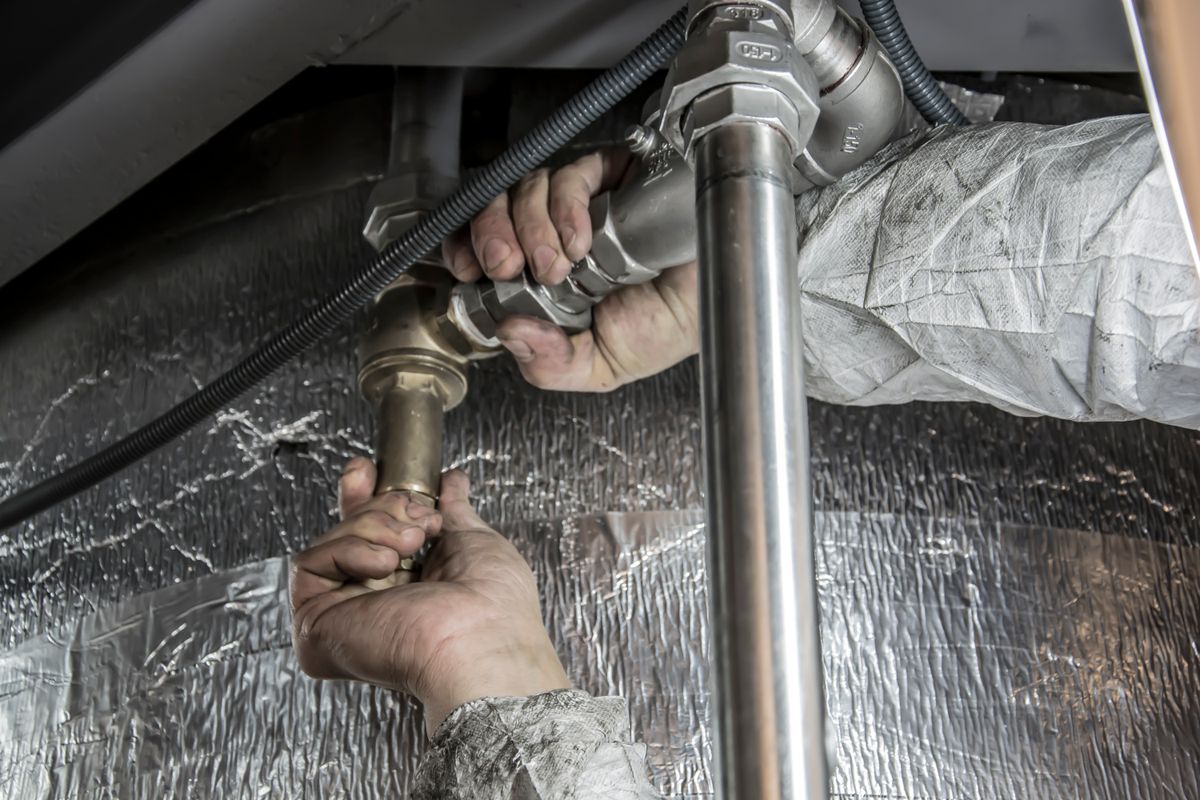 Mains d'un plombier installant des tuyaux en acier