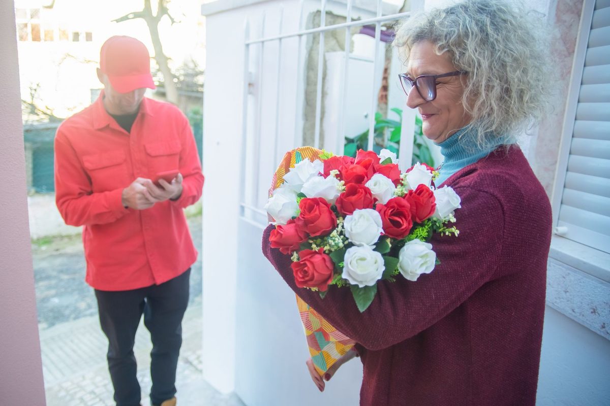 Livreur remettant un bouquet de roses sur le pas d'une porte