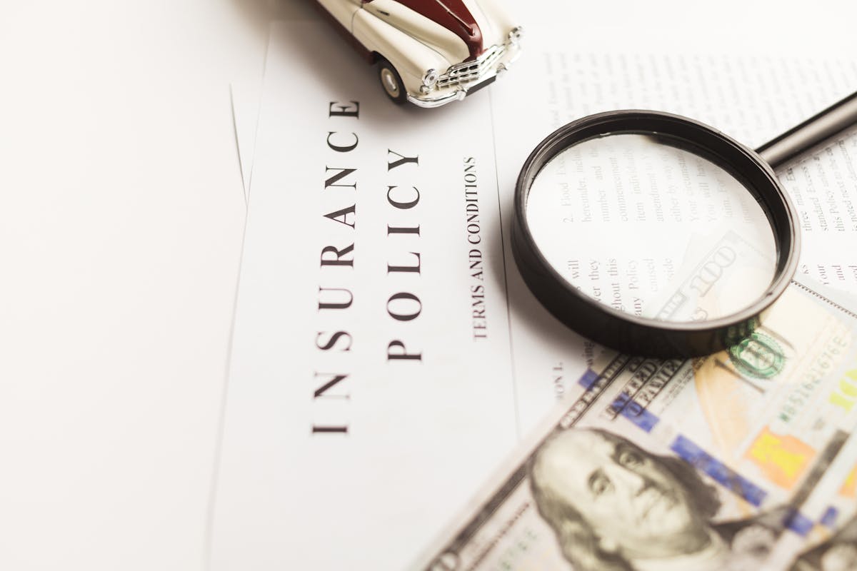 Contrat d'assurance automobile avec loupe, billets et voiture miniature