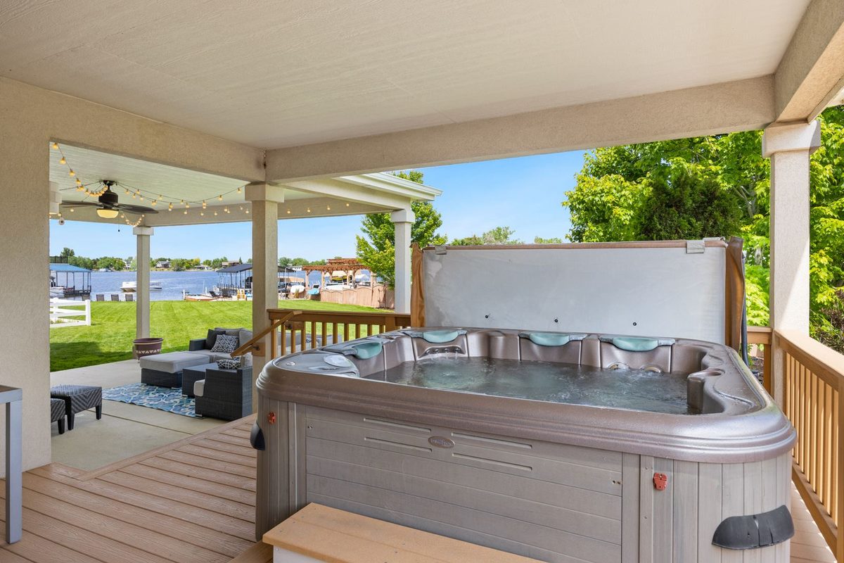 Spa installé sous un abri de terrasse, face à un plan d'eau