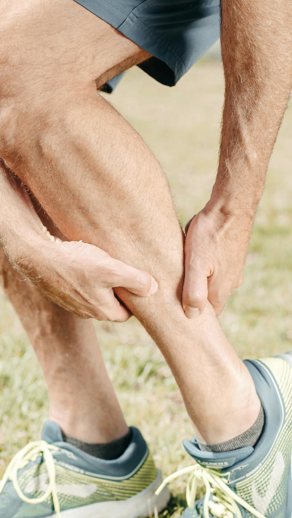 Sportif se massant le mollet après une crampe musculaire