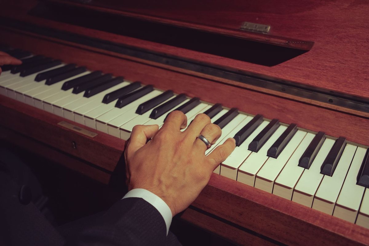 Mains posées sur le clavier d'un piano droit ancien