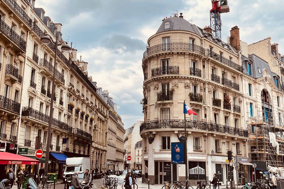 Rue parisienne animée bordée d'immeubles haussmanniens