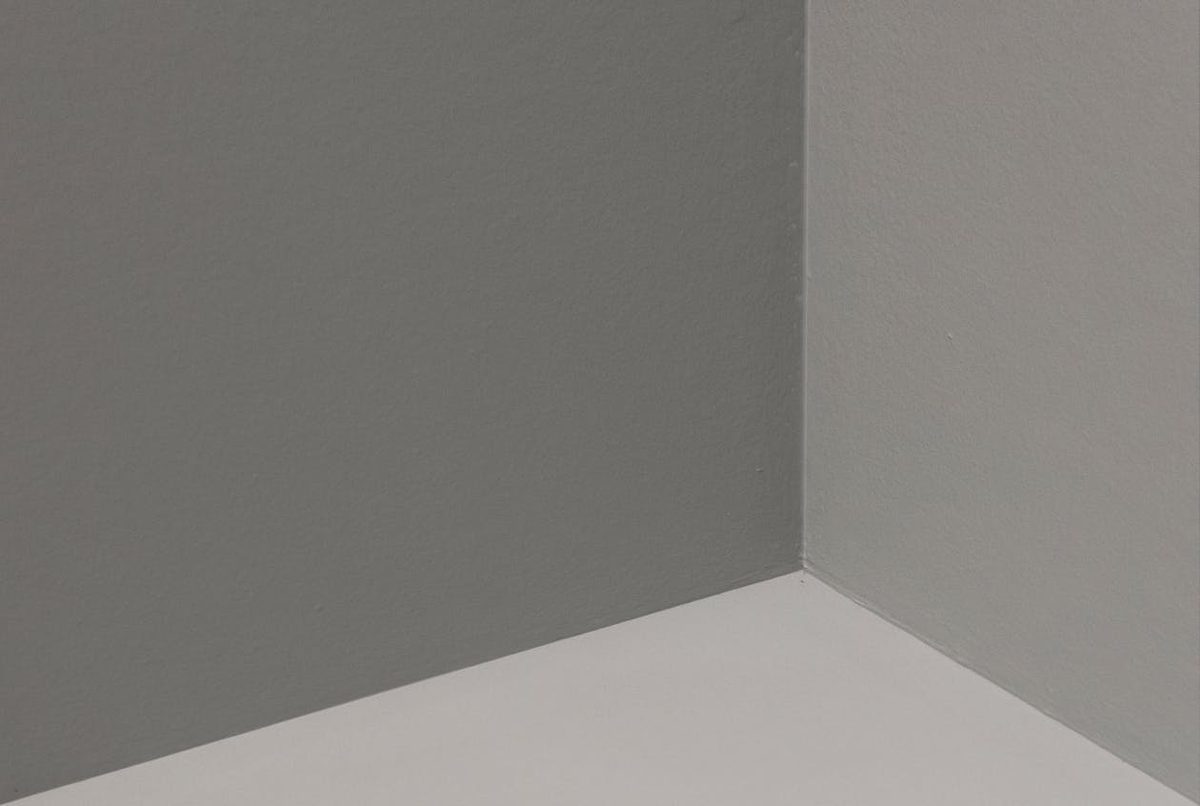 Angle de mur avec baguette d'angle métallique en cours de pose