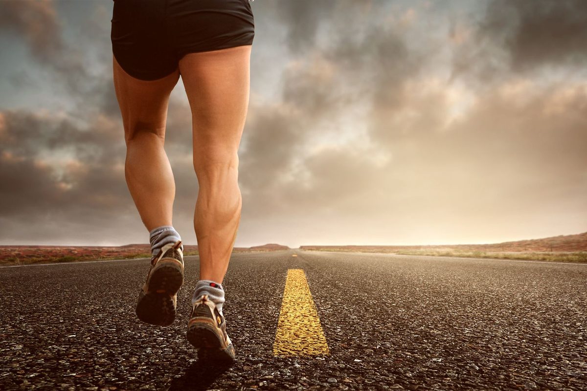 Jambes d'un coureur sur la route au coucher du soleil