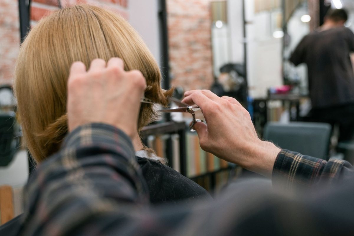 Coiffeuse travaillant une chevelure blonde au salon
