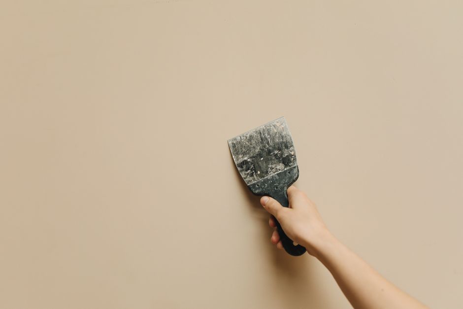 Personne retirant une bande de papier peint d'un mur