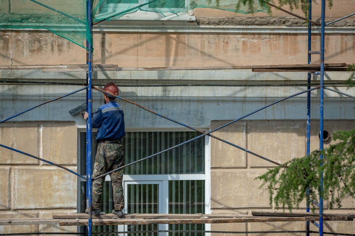 Ouvrier sur un échafaudage travaillant la façade d'un immeuble
