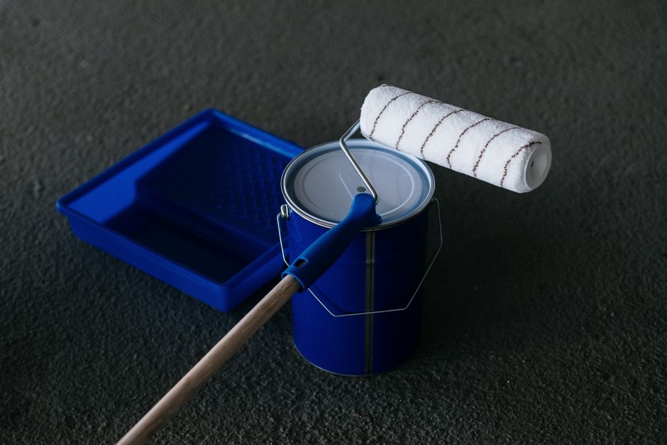 Pot de peinture et rouleau devant un mur en cours de peinture