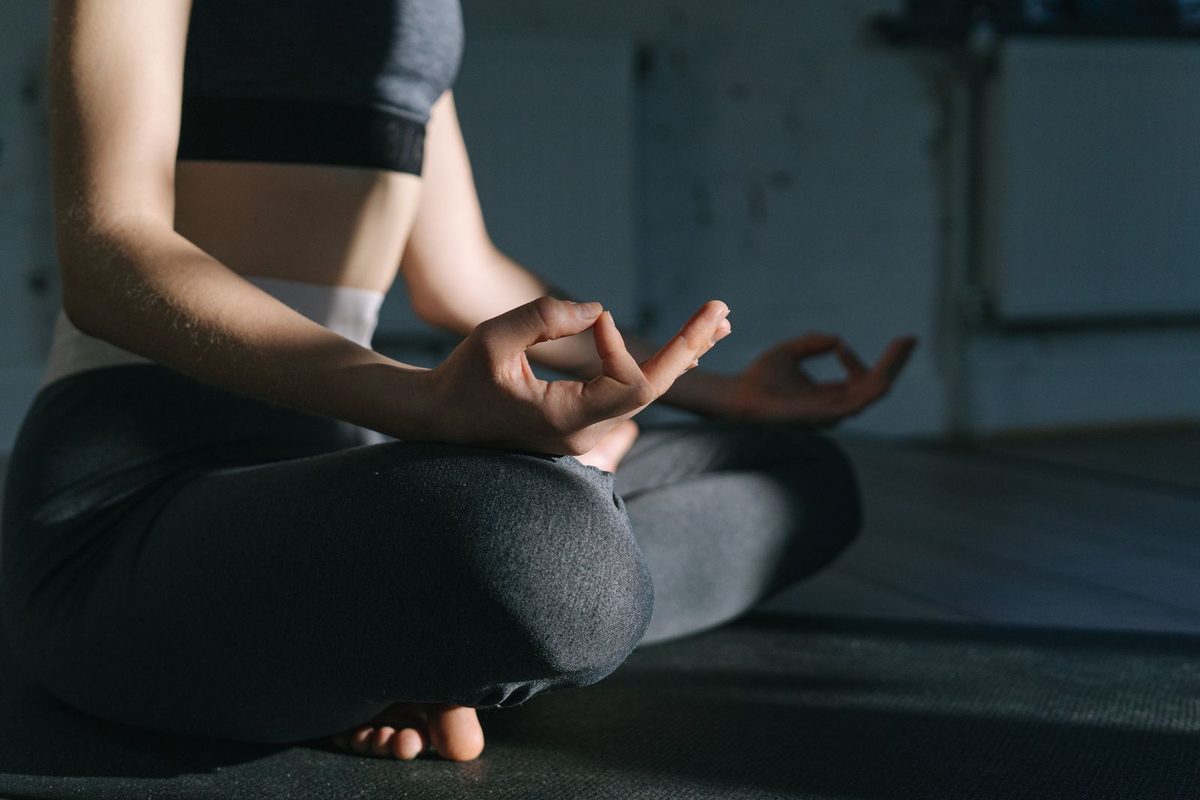 Personne assise en tailleur, mains ouvertes, en méditation