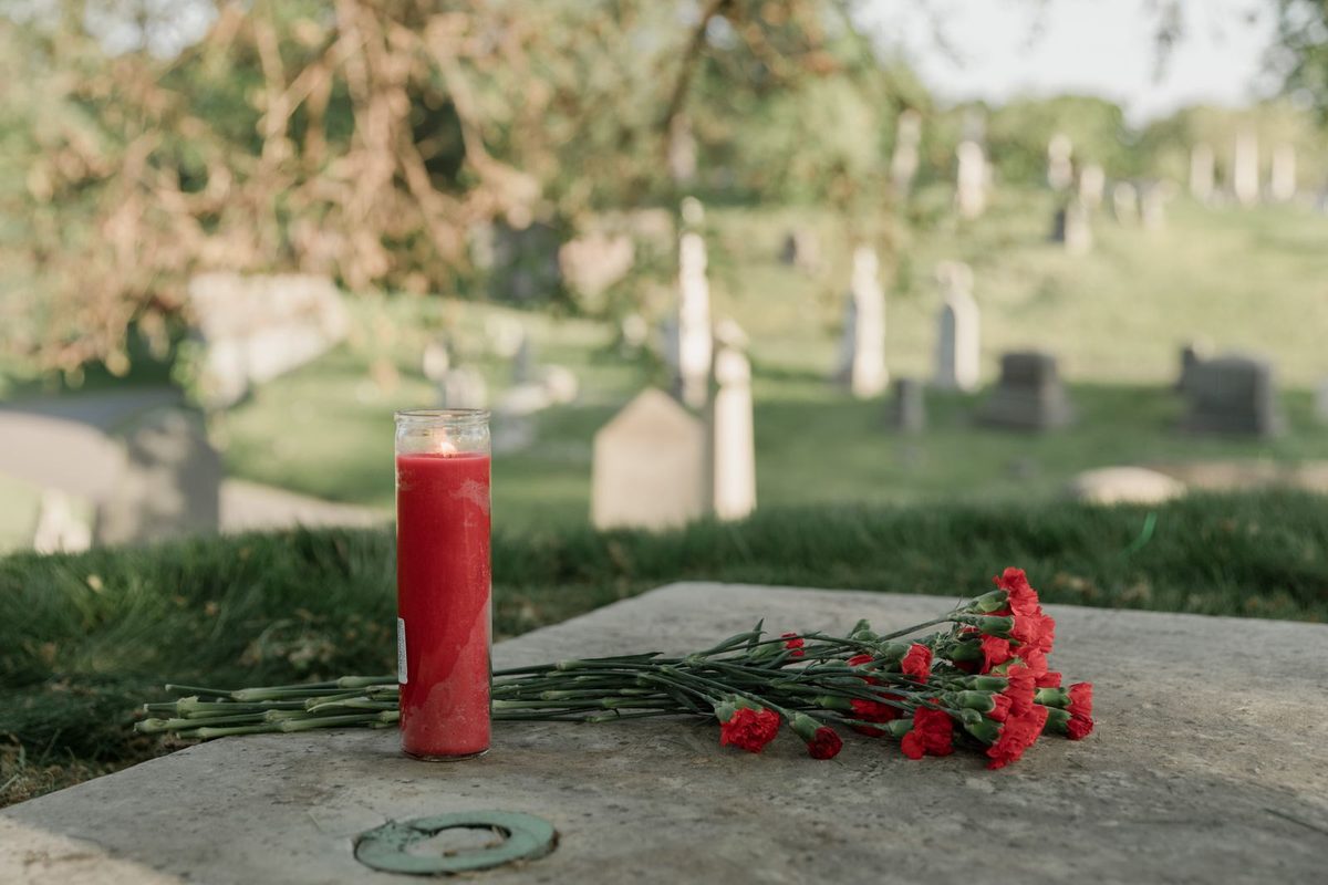 Bougie rouge et œillets déposés dans un cimetière