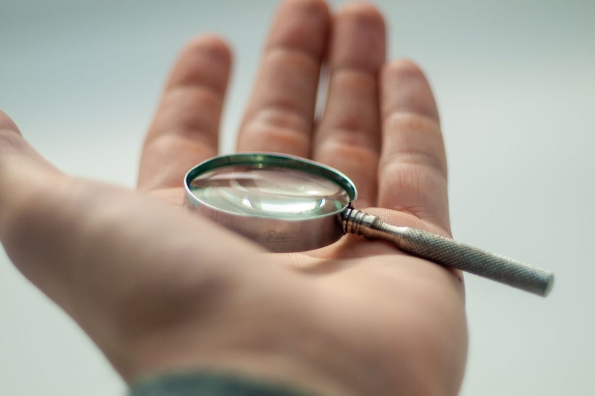 Paume de main ouverte, tenant une loupe