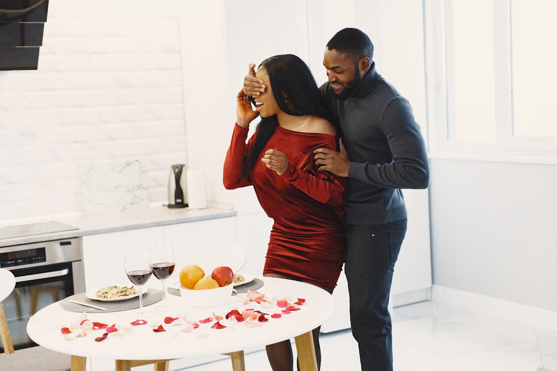 Couple qui partage un moment surprise romantique à la maison avec pétales et bougie