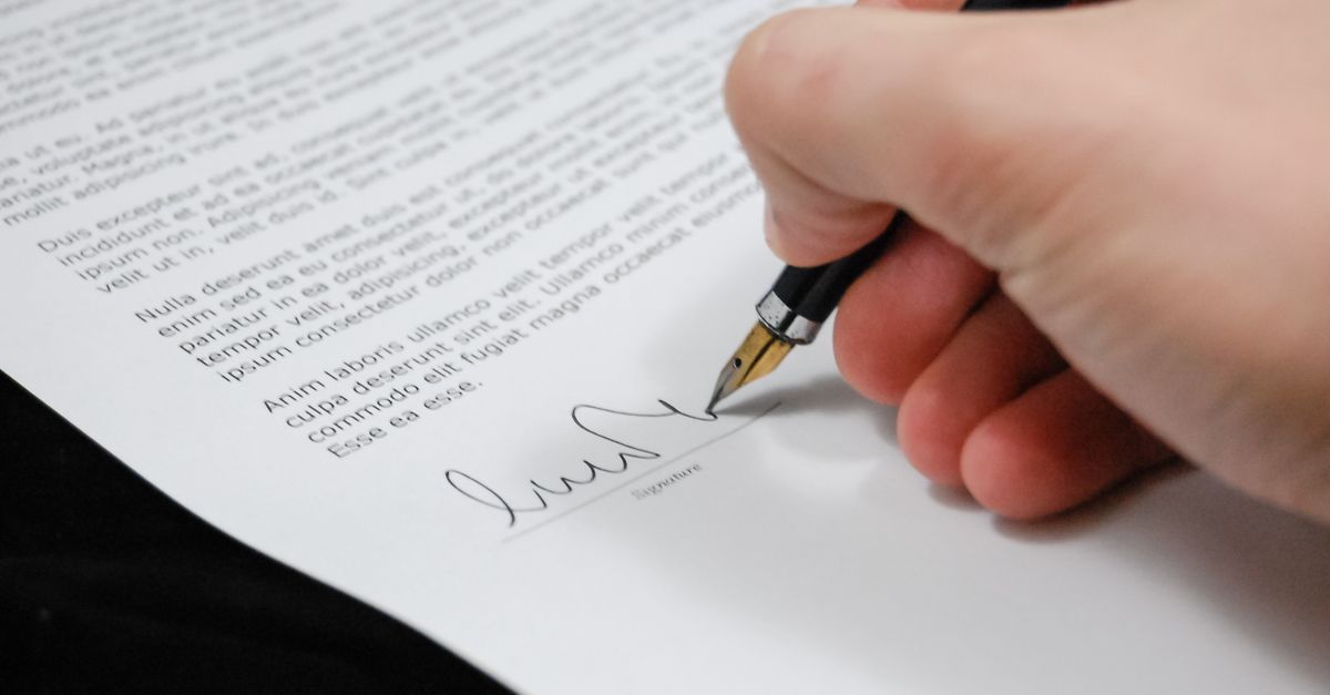 Personne rédigeant une procuration sur un bureau avec des documents officiels