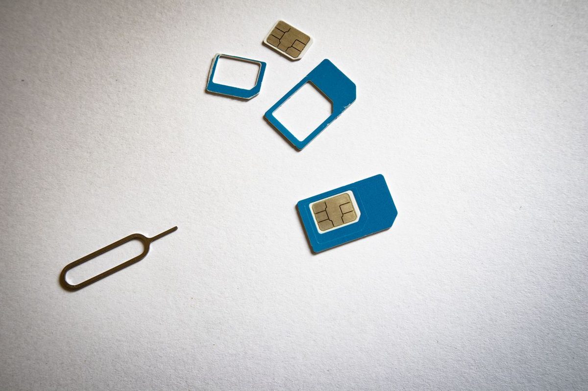 Cartes SIM de différents formats et outil d'éjection posés sur une surface blanche