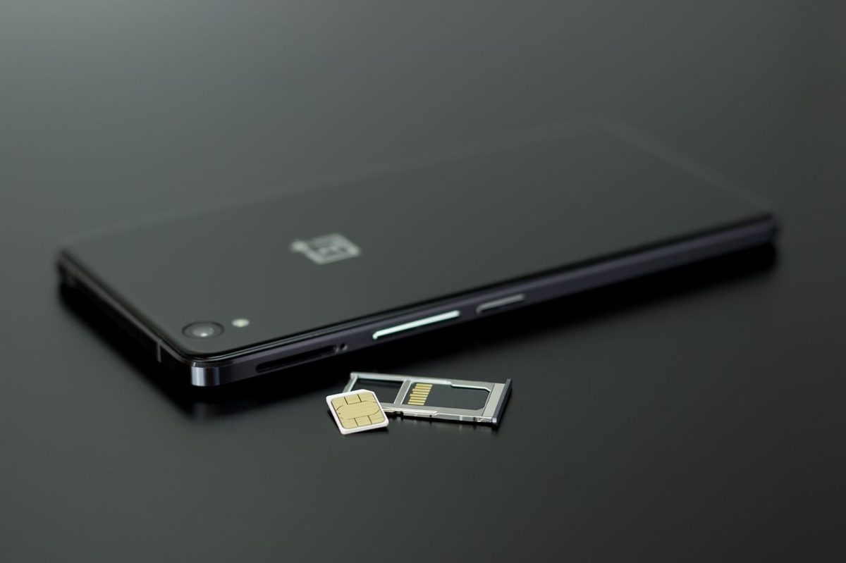 Smartphone posé sur une table avec son tiroir et sa carte SIM