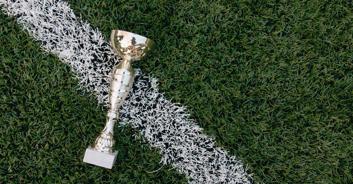 Trophée doré posé sur la pelouse au bord d'une ligne blanche